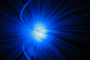 Photograph of a bunch of fiber optic cable with base glowing blue.